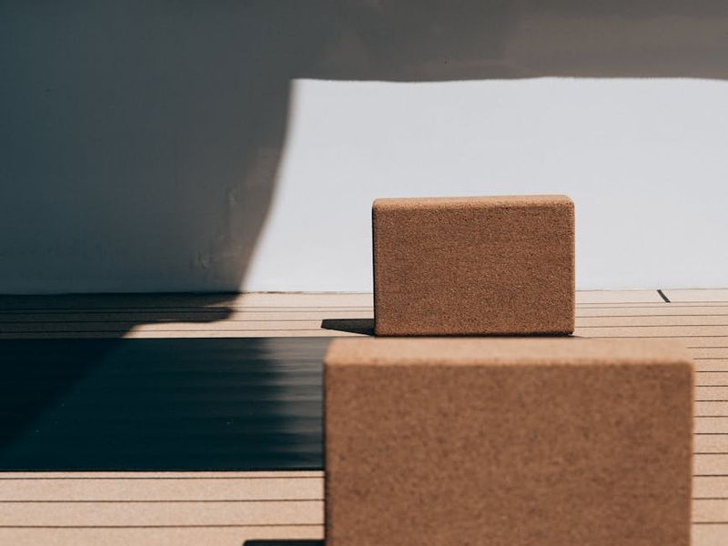 Minimalist yoga mat and blocks on a wooden floor.
